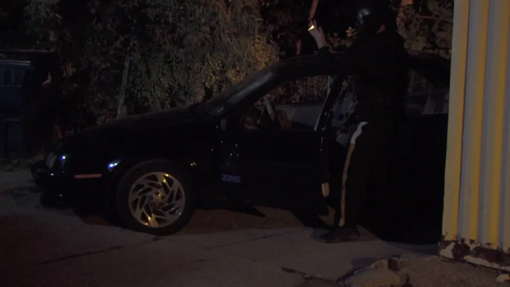Man in the Mask & car in alley.